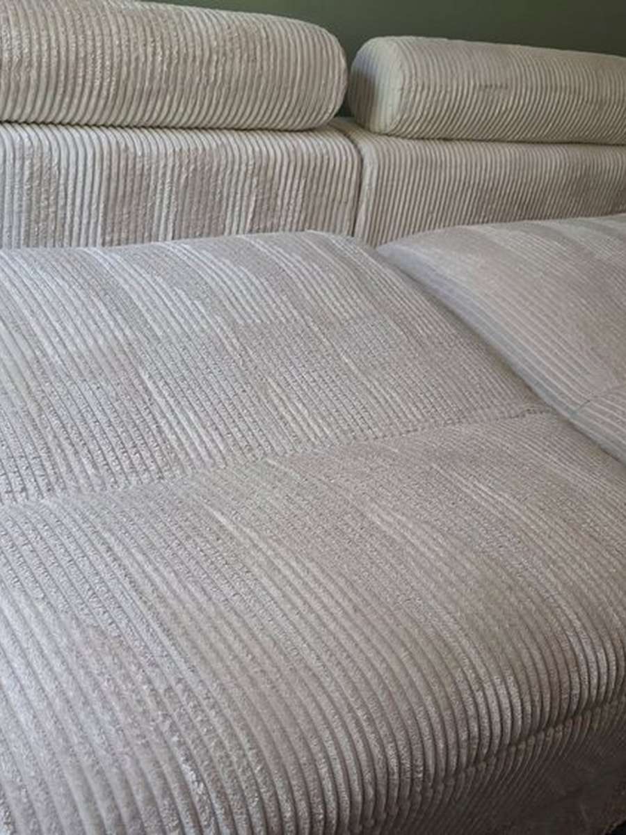 A close view of a pale corduroy sectional sofa after cleaning, the ribbed fabric even in color across the seat and back cushions.